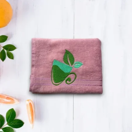 Purple towel with green tea cup and leaf embroidery on light wooden background
