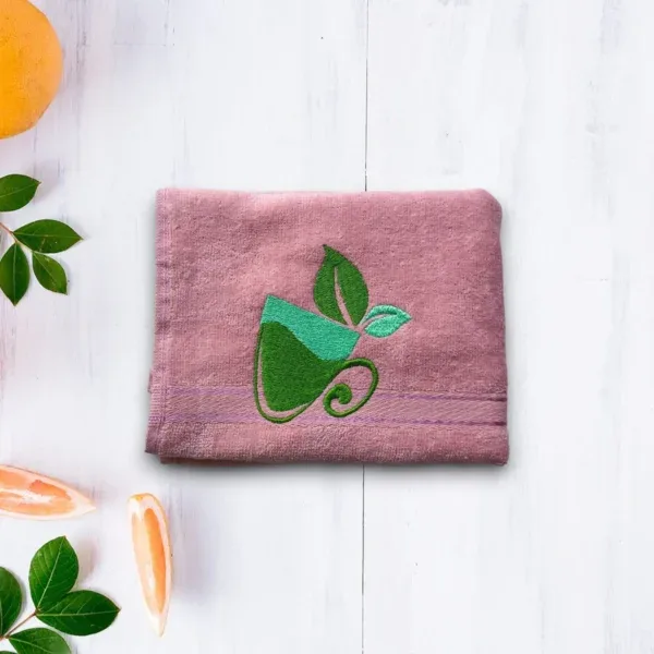 Purple towel with green tea cup and leaf embroidery on light wooden background