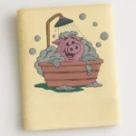 Cream kids bath towel with cartoon pig taking a bubble bath under shower embroidered design
