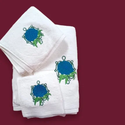 White towel set with blue flower embroidery and green leaves on maroon background