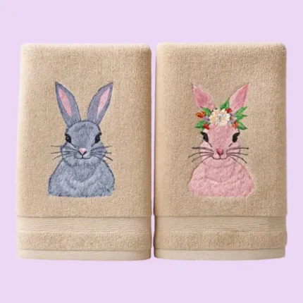 Beige towels with grey bunny and pink bunny with flower crown embroidery on pastel background