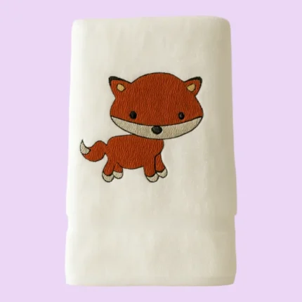 White towel with adorable orange fox embroidery on pastel background