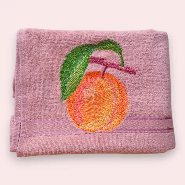 Pink cotton towel with embroidered orange fruit and green leaf design