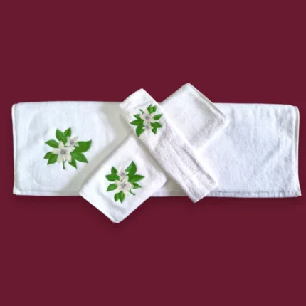 White towel set with green and white flower embroidery on maroon background